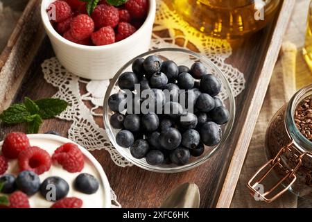 Fresh blueberries in a bowl, with flax seeds, raspberries and cottage cheese in the bacckground Stock Photo