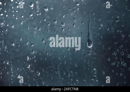 Raindrops running down a window pane on a dark, rainy day, full frame background, concept for depressing weather, copy space, selected focus Stock Photo