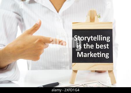 A woman pointing at a blackboard with the word Storytelling is the best Marketing written on it Stock Photo