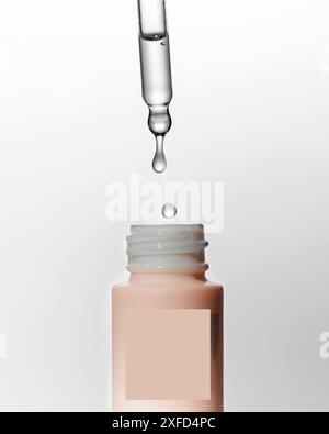 Hyaluronic acid drops fall from pipette into mockup bottle Stock Photo