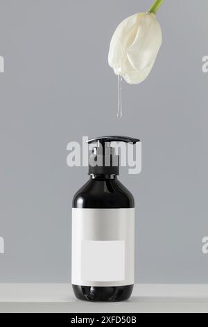 Dripping clear gel from tulip onto dispenser bottle on light Stock Photo