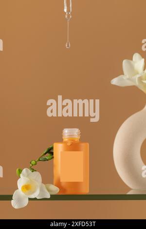 Dripping clear serum from pipette into bottle with freesias Stock Photo