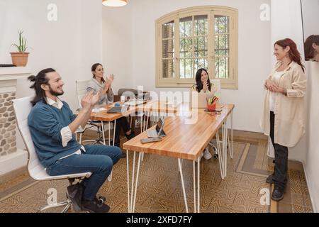 A group of diverse professionals applauding a successful presentation in a bright office environment, showing teamwork and appreciation. Stock Photo