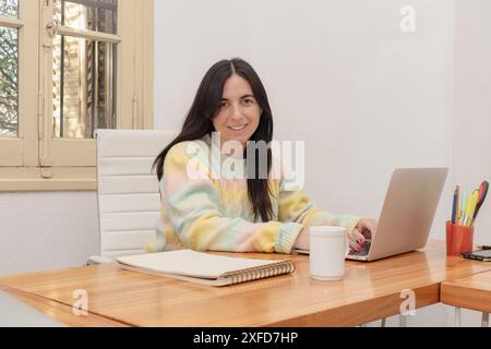 Portrait of a smiling young woman working on laptop computer at home Stock Photo