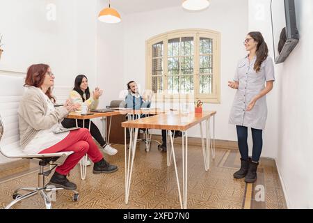 A dynamic office scene captures a successful project presentation with team members congratulating their teammate with applause. Stock Photo