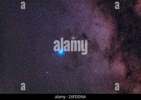 Wide field view of constellation Aquila, with the bright blue-white star Altair at centre, the red star Tarazed above, and the dimmer star of the trio, Alshain, below. Above Tarazed is the distinct dark nebula known as Barnard's E. Named for Edward Emerson Barnard who photographed and catalogued these dark nebulas in the early 20th century, the 'E' is officially B142 and B143. A large dark lane in the Milky Way at right contrasts with the rich starclouds here in Aquila. Photographed from southern Alberta, Canada on 16 May 2023. Stock Photo