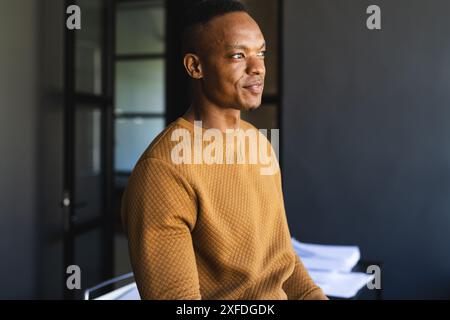 Smiling businessman in casual attire sitting in modern office setting Stock Photo