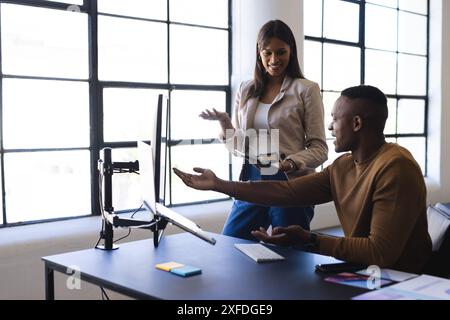 Collaborating on project, colleagues discussing work at computer in modern office Stock Photo