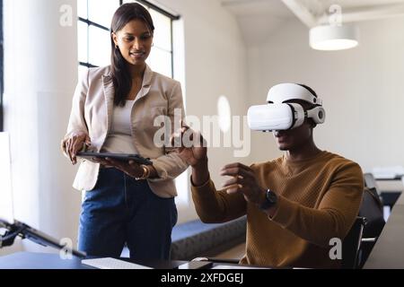 Using VR headset, man interacting while woman holding tablet in office Stock Photo