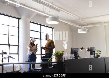 Using VR headset, business colleagues discussing project in modern office setting Stock Photo