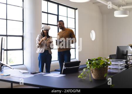 Using VR headset, business colleagues discussing project with tablet in office Stock Photo
