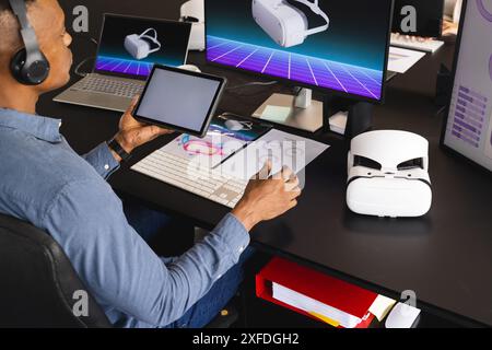 Using tablet and VR headset, man working on virtual reality project in office Stock Photo