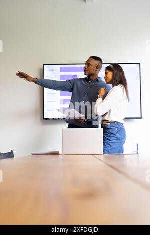 Presenting data on screen, colleagues discussing project in modern office setting, copy space Stock Photo