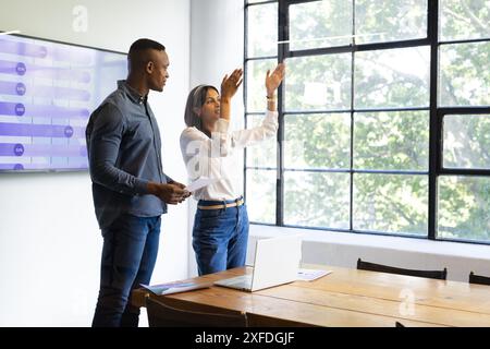 Presenting data on screen, business colleagues discussing project in modern office, copy space Stock Photo