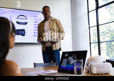 Presenting data, man holding tablet and explaining VR headset statistics in meeting Stock Photo