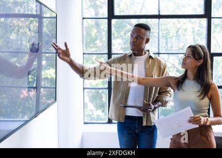 Presenting data on screen, colleagues discussing project in modern office setting, copy space Stock Photo