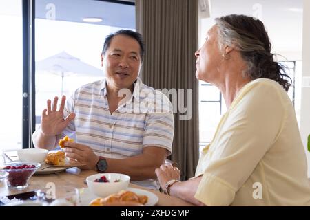 Senior couple enjoying breakfast and having conversation at dining table Stock Photo