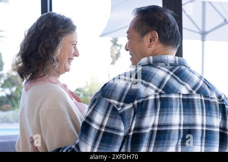 Enjoying vacation together, smiling senior couple standing by window Stock Photo