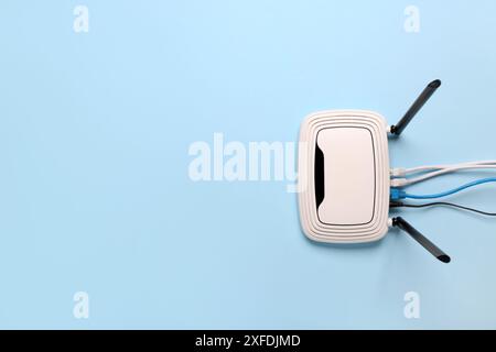 Modern wi-fi router with cables on blue background Stock Photo