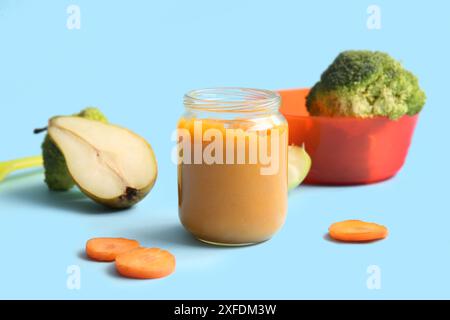 Glass jar of healthy baby puree and ingredients on color background Stock Photo