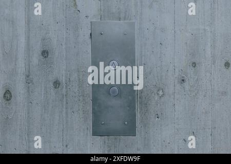 Button of a passenger lift or elevator on interesting concrete wall with wood texture. Buttons for lift operation, frontal view Stock Photo