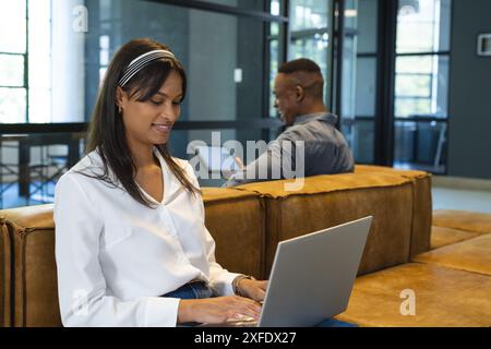 Working on laptops, business colleagues collaborating in modern office space Stock Photo