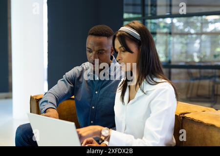 Collaborating on laptop, business colleagues discussing project in modern office Stock Photo