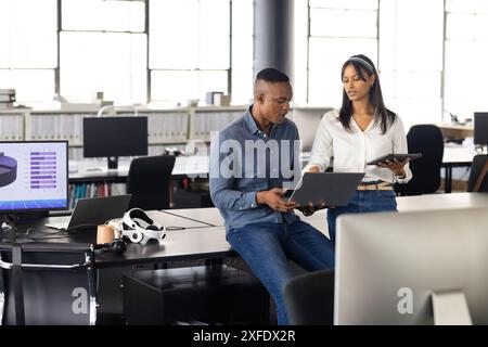 Collaborating in office, colleagues using laptop and tablet for project discussion Stock Photo
