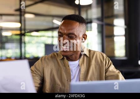 Smiling businessman reviewing documents and using laptop in modern office Stock Photo