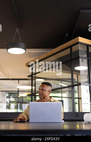 Working in modern office, man using laptop and looking thoughtful, copy space Stock Photo