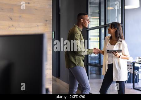 Business professionals shaking hands, woman holding tablet in modern office, copy space Stock Photo