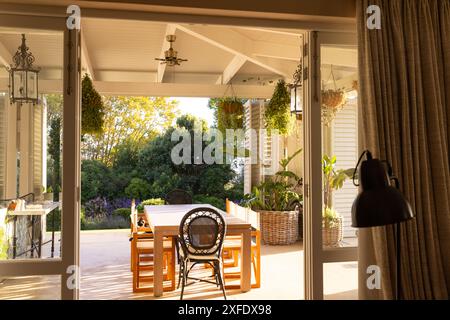 Sunlight illuminating cozy patio with dining table and hanging plants, copy space Stock Photo