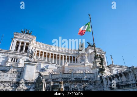 The Vittoriano, a large marble monument in Rome, Italy, is seen with the Italian flag flying high above. The monument was built to honor Victor Emmanuel II, the first king of a unified Italy. Stock Photo