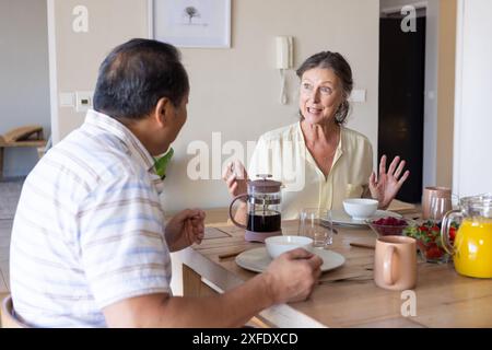 Having breakfast, senior couple enjoying conversation at dining table with coffee and juice Stock Photo