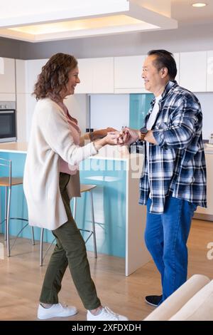 Senior couple dancing together in modern kitchen, enjoying their vacation Stock Photo