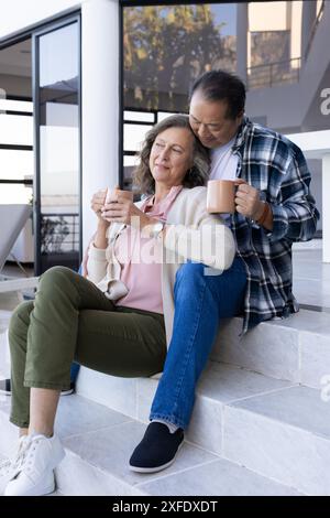 Senior couple sitting on steps, enjoying coffee and relaxing together Stock Photo