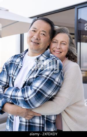 Senior couple hugging and smiling outdoors during vacation, enjoying time together Stock Photo
