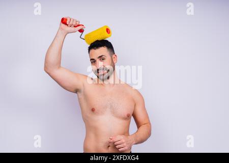 Young employee handyman using paint roller hold face isolated on background studio. Stock Photo