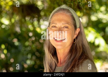 Smiling mature woman with long hair and headband enjoying outdoor nature Stock Photo