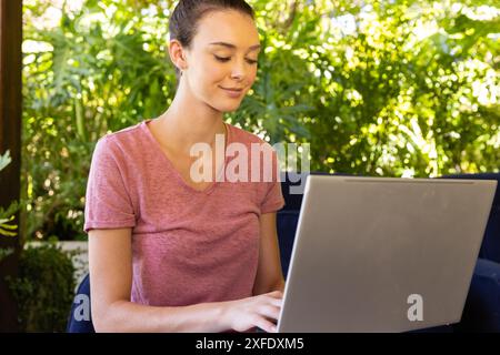 Working from home, young woman using laptop in outdoor garden setting Stock Photo