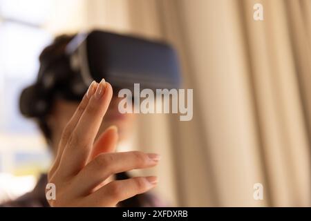 Using VR headset, woman interacting with virtual environment at home Stock Photo