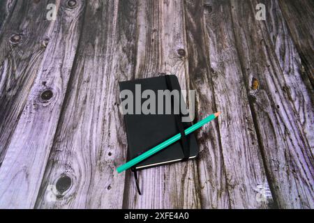 Black notebook with green pen on a wooden table.  Stock Photo