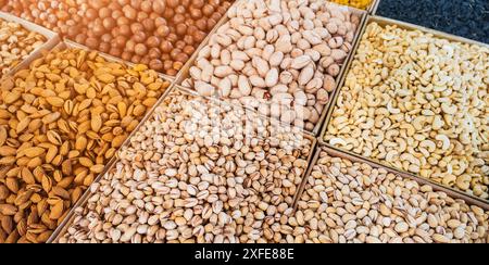 assortment of variety nuts on counter at oriental Uzbek food bazaar. Almonds, pistachios, hazelnuts, macadamia, pecans and cashews in market stall Stock Photo