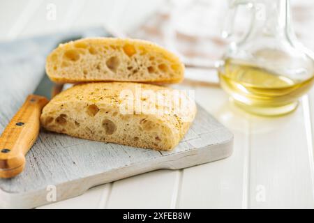 Italian ciabatta bread on cutting board on a white table. Stock Photo