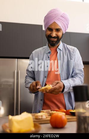 Spreading butter on bread, man preparing breakfast in modern kitchen Stock Photo