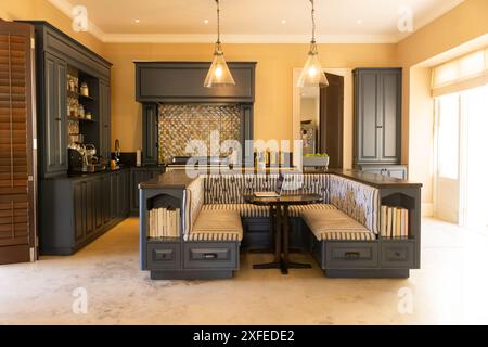Modern kitchen with built-in seating area and pendant lights, cozy and inviting, copy space Stock Photo