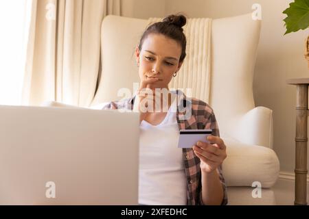 Shopping online, young woman holding credit card and using laptop at home, copy space Stock Photo