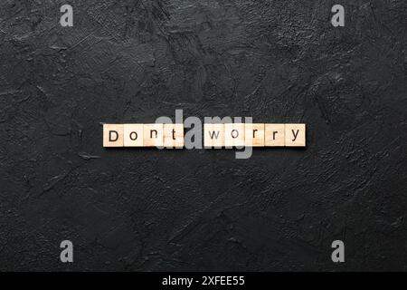 Don't worry word written on wood block. Don't worry text on cement table for your desing, Top view concept. Stock Photo