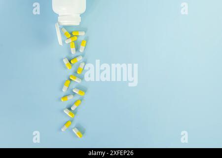Top view of white bottle with the yellow pills on the blue background. Copy space. Stock Photo