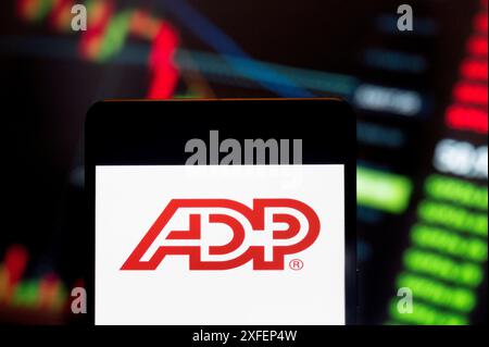 China. 23rd June, 2024. In this photo illustration, the American provider of human resources management software and services company, Automatic Data Processing (ADP, NASDAQ: ADP), logo seen displayed on a smartphone with an economic stock exchange index graph in the background. (Credit Image: © Budrul Chukrut/SOPA Images via ZUMA Press Wire) EDITORIAL USAGE ONLY! Not for Commercial USAGE! Stock Photo